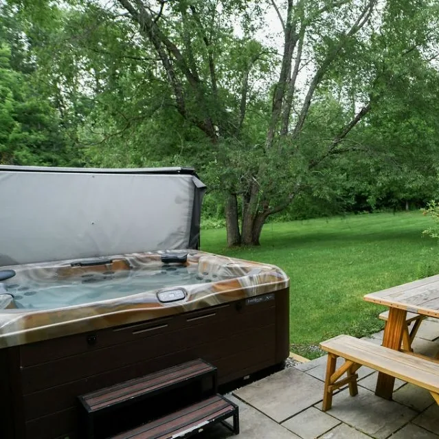Hot tub with cover propped open on the patio
